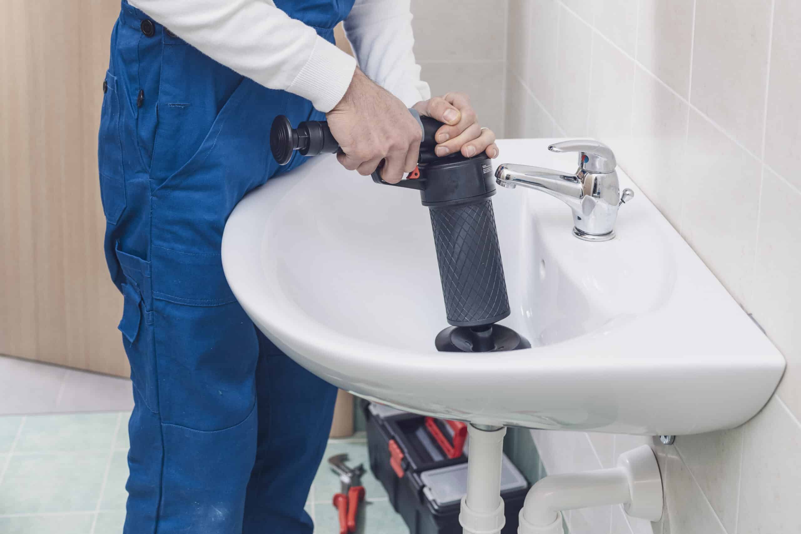 Professional plumber unclogging a sink using an air pump plunger
